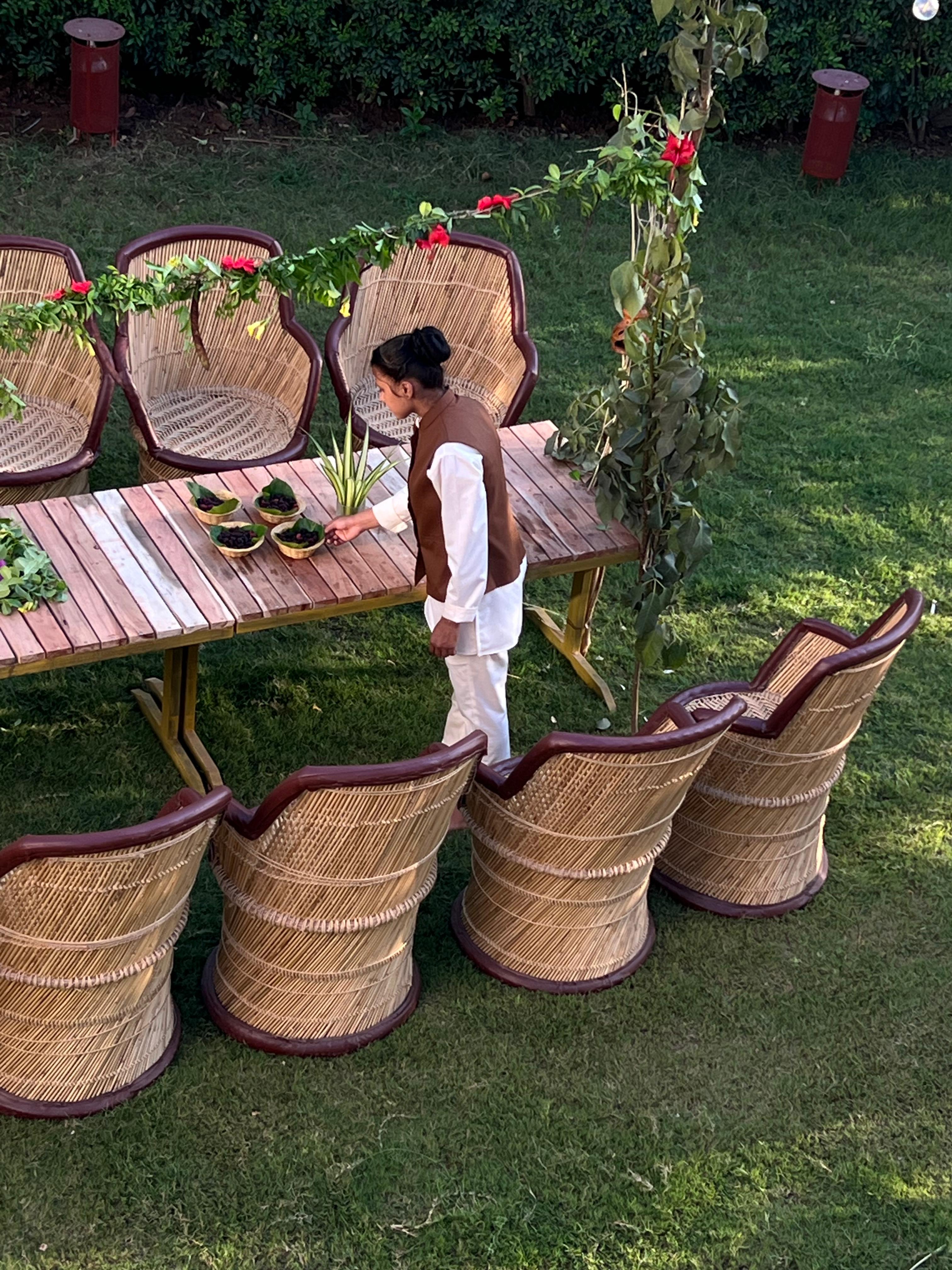 Staff setting a table on the lawn among wicker chairs